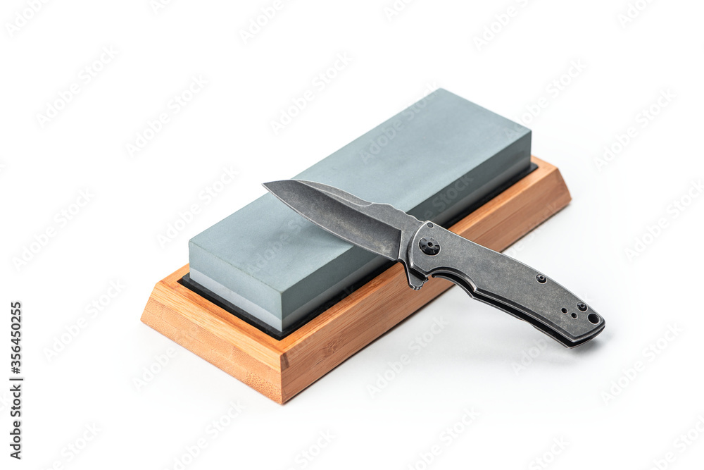 Black pocket knife and a whetstone isolated on white Black pocket knife and a whetstone isolated on white