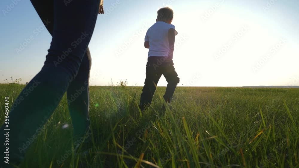 Young loving mom plays with her son outdoors. The child is happy and smiling. Happy family running around on the green grass, enjoying, having fun. The concept is a healthy lifestyle. Young loving mom plays with her son outdoors. The child is happy and smiling. Happy family running around on the green grass, enjoying, having fun. The concept is a healthy lifestyle.