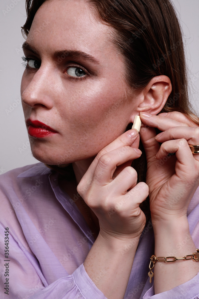 Attractive and beautiful woman with a high hairstyle is wearing a purple top. Big golden shine earrings jewellery. Isolated. Attractive and beautiful woman with a high hairstyle is wearing a purple top. Big golden shine earrings jewellery. Isolated.