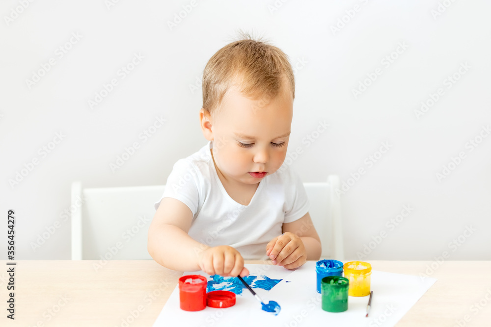 child boy 2 years old sitting at a table on a white isolated background and paints, early development, place for text child boy 2 years old sitting at a table on a white isolated background and paints, early development, place for text