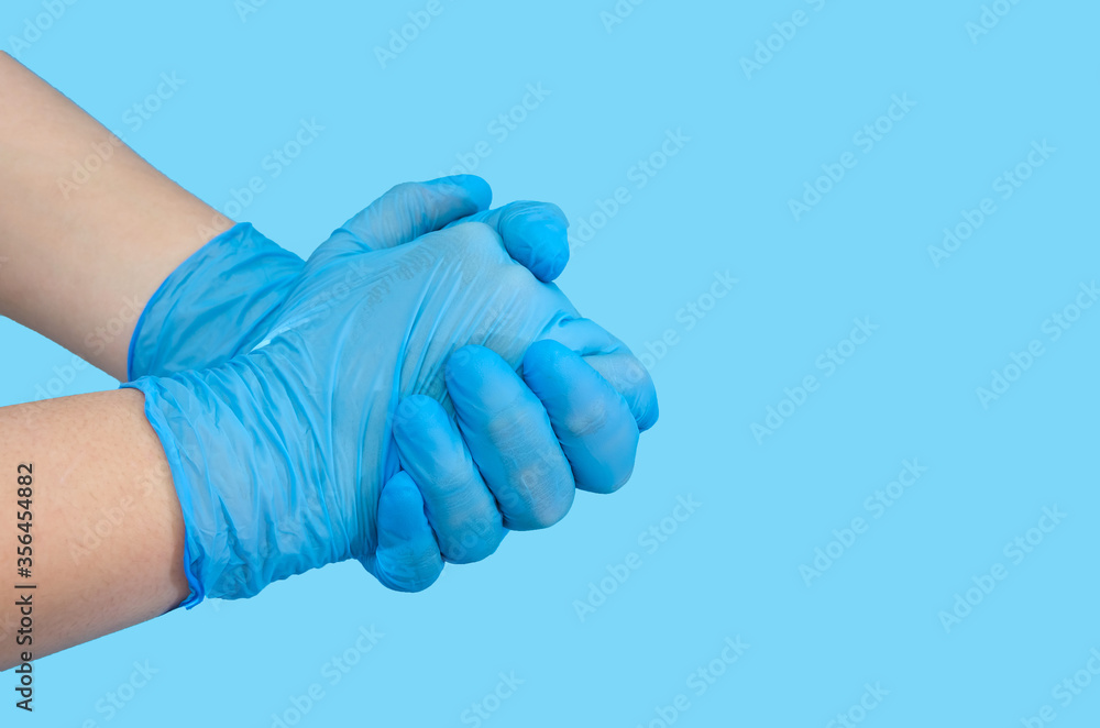 Individual protection products vinyl disposable gloves in the spread of virus and protection against infections. Women 's hands in gloves. Copy of space. Blue background.