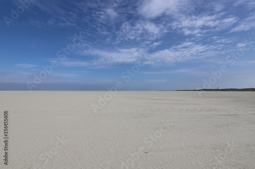 A beautiful blue sky over a wide white beach.