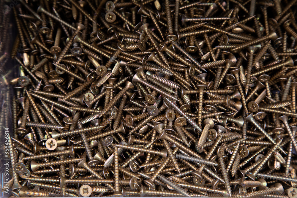 Macro of bronze self-tapping screws for wood working. Strong screws on a wooden table Macro of bronze self-tapping screws for wood working. Strong screws on a wooden table