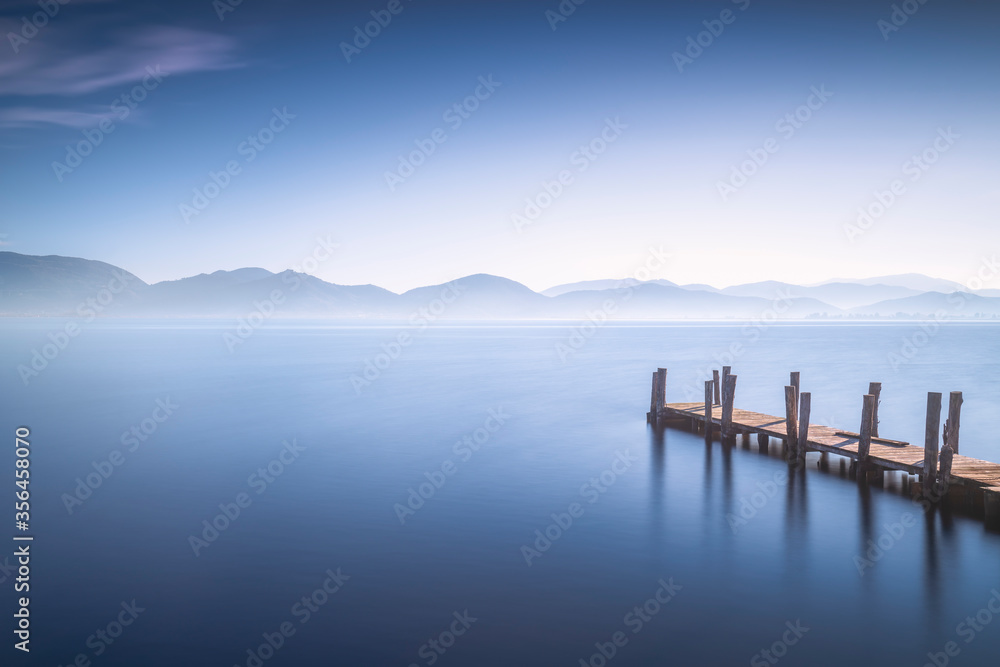 Wooden pier or jetty at sunset and sky reflection on water. Versilia Tuscany, Italy