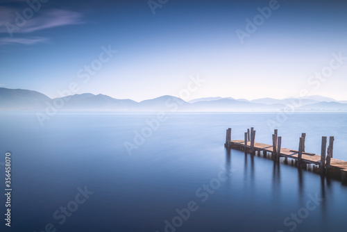 Wooden pier or jetty at sunset and sky reflection on water. Versilia Tuscany, Italy © stevanzz