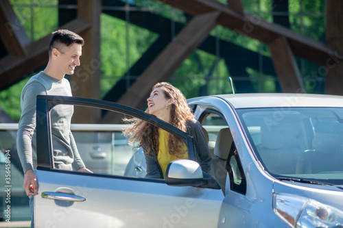 Young pretty woman opening the car door and talking to the young man photo