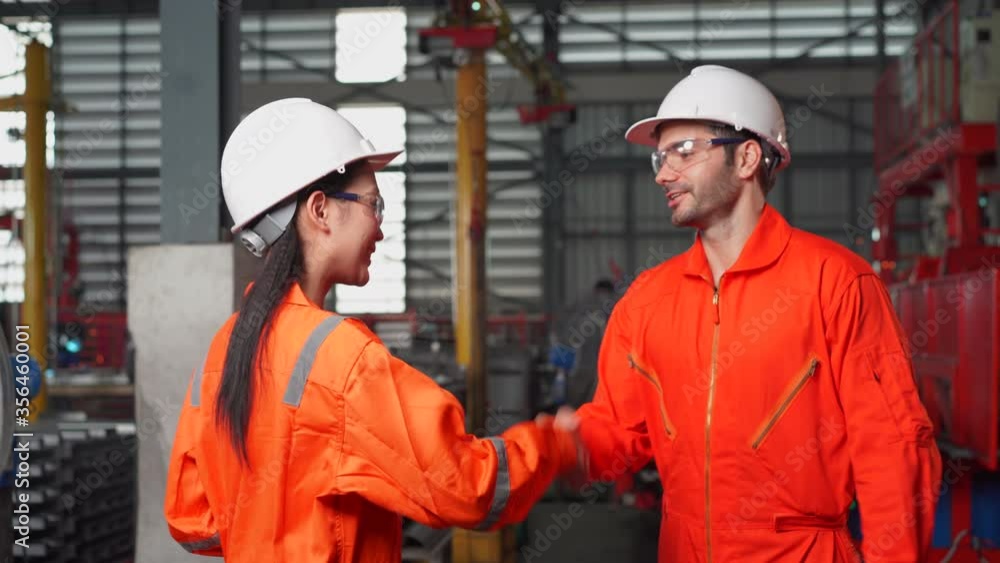 Hands held camera technique of two engineers shake hands at factory Hands held camera technique of two engineers shake hands at factory