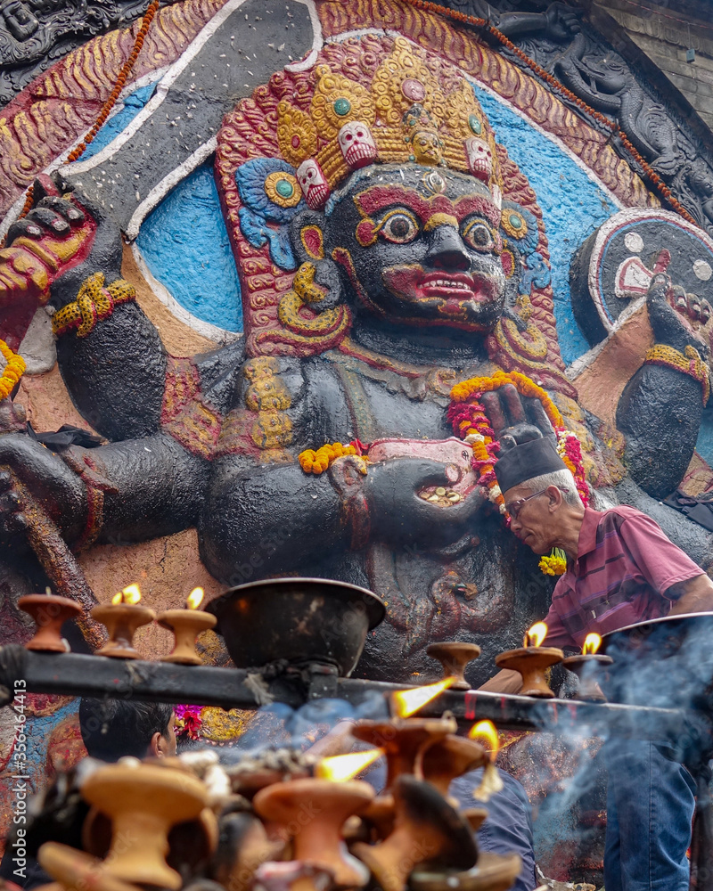Hindu state of Lakshmi on the side of a temple with oil lamps burning
