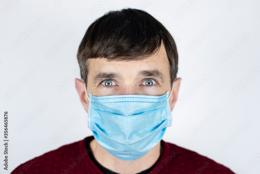 A man with big frightened eyes with a medical mask on his face, his whole face is covered with a mask. The man is frightened by the bad environment and dangerous viruses everywhere A man with big frightened eyes with a medical mask on his face, his whole face is covered with a mask. The man is frightened by the bad environment and dangerous viruses everywhere