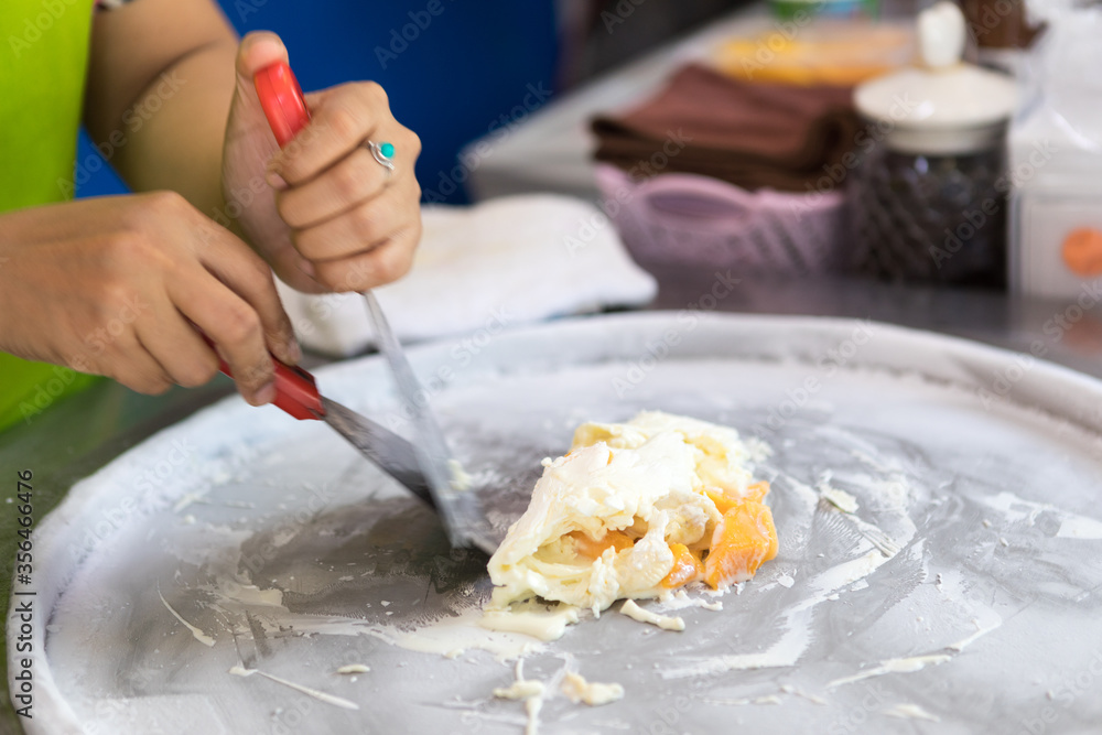 process of making fried ice-cream. Thailand stir-fried ice cream rolls at freeze pan. Organic, natural rolled ice cream, hand made dessert. Fried ice cream machine with steel chilled pan.