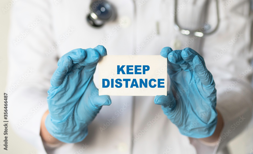 A doctor hold card in his hands with text KEEP DISTANSE, protect from Coronavirus or Covid-19 epidemic. Medicine concept A doctor hold card in his hands with text KEEP DISTANSE, protect from Coronavirus or Covid-19 epidemic. Medicine concept