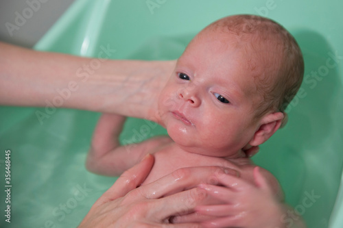 A premature one and a half month old premature being bathed by his mother.