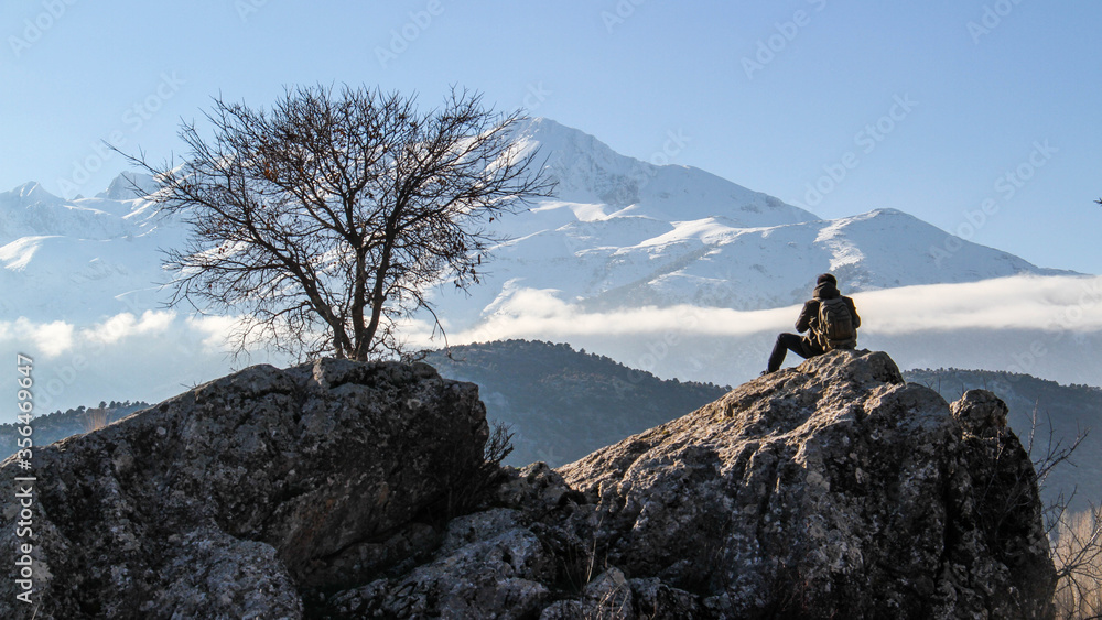 A hiker sitting on a rock at a mountain