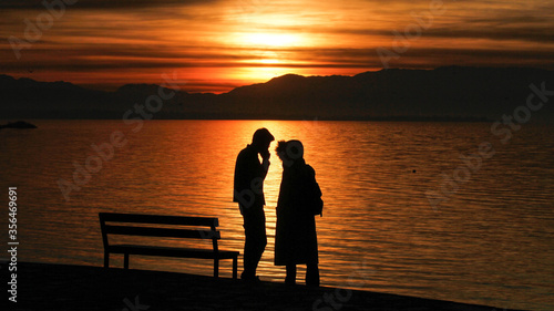 Silhouette of lovers watching the beautiful sunset on the lake