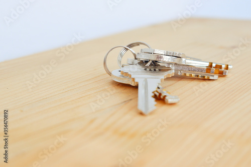 Bunch of keys on a shaped keychain at wooden table background. Concept for real estate or renting home with copy space,Close up.
 photo