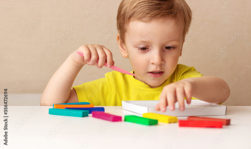Caucasian baby blond sculpts from children's dough for sculpting at home at the table, children and creativity, the development of fine motor skills Caucasian baby blond sculpts from children's dough for sculpting at home at the table, children and creativity, the development of fine motor skills
