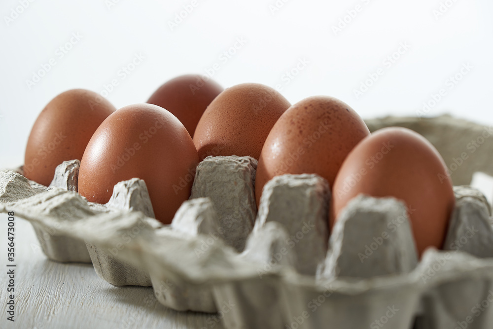 Eggs close up in protective container on white background. Foreground and background in blur. Eggs close up in protective container on white background. Foreground and background in blur.
