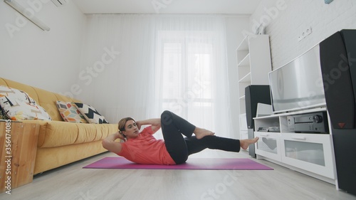 Androgynous Transgender beautiful young gay man doing abs crunch exercise on mat at home.