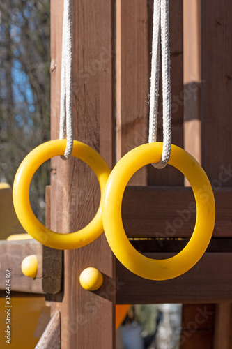 Children's gymnastics rings yellow hang on a wooden Playground