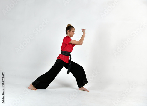 beautiful girl in black and red does exercises for mastery of martial arts