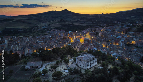 Aerial view with the Drone on Castellana Sicula, in the Madonie park at blue hour with the lights of the village on and the last light of the sunset