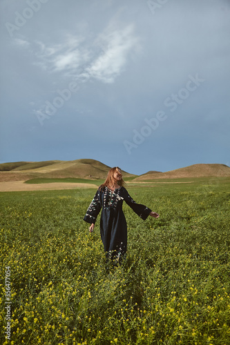 Freedom. Young cheerful woman in traditional dress posing in a cultivated wheat field on a summer day