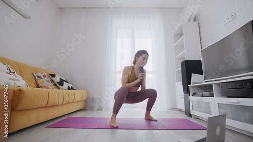 On-line work out woman using internet services with help of her instructor. Slim woman does classic squats