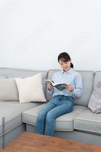ソファに座って本を読んでいる女性