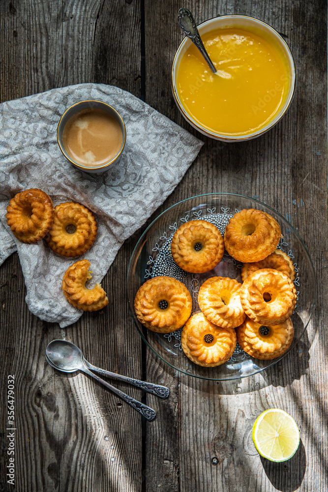 Shaped mini bundt cakes with lemon curd on old wooden table. Shaped mini bundt cakes with lemon curd on old wooden table.
