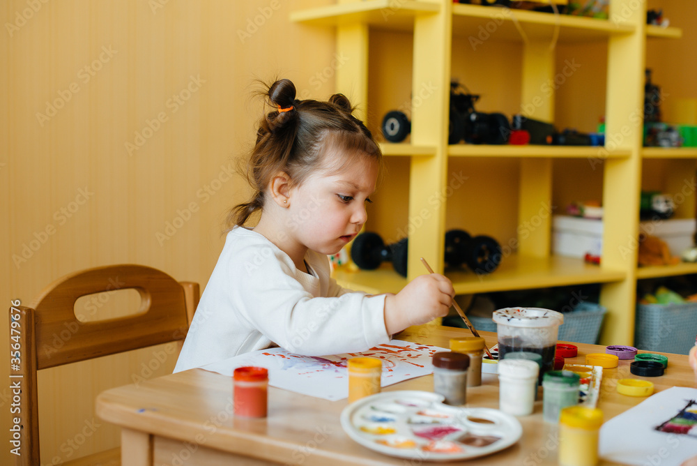A cute little girl is playing and painting in her room. Recreation and entertainment
