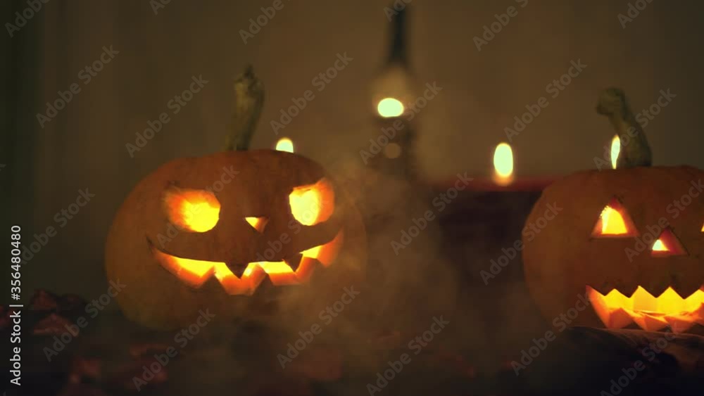 Halloween two pumpkins. Camera movement to the left. Background candles and kerosene lamp. Smoke coming out of the floor. Halloween art design. Halloween two pumpkins. Camera movement to the left. Background candles and kerosene lamp. Smoke coming out of the floor. Halloween art design.