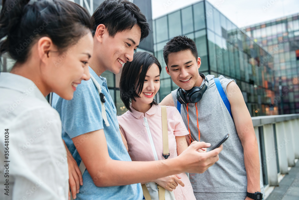Outdoor four college students watch mobile phone Outdoor four college students watch mobile phone