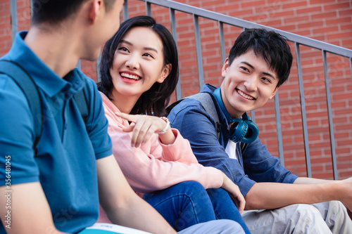 College students were sitting outside of chatting on the stairs photo