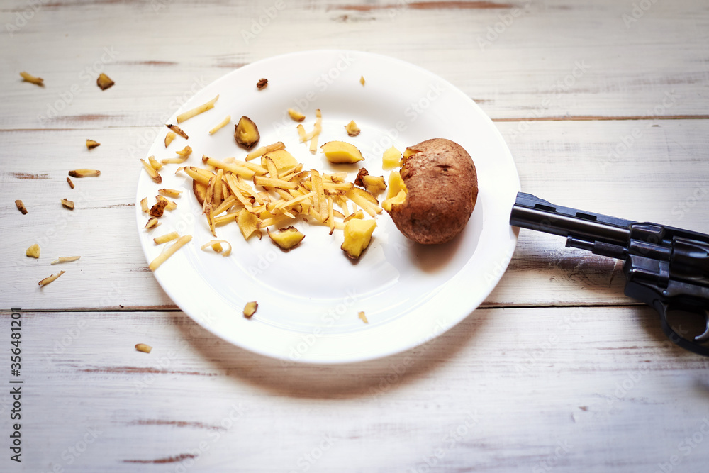 Fototapeta premium Despair, tired of cooking in the kitchen concept. A shot from a pistol at a potato.