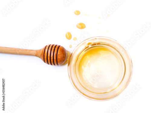 Top view of drops of honey and dipper wooden stick on white background