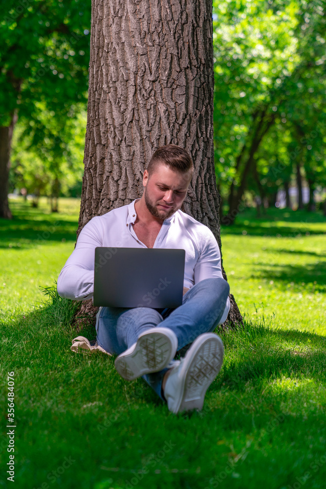 a man of European appearance works remotely using a laptop while he is in the park a man of European appearance works remotely using a laptop while he is in the park