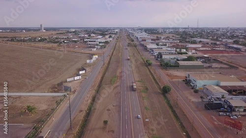 Drone aerial view of cars and trucks driving on BR 163 road and Sinop city skyline in a sunny summer day. Mato Grosso, Brazil. Concept of transport, travel, transportation, logistics, economy. photo
