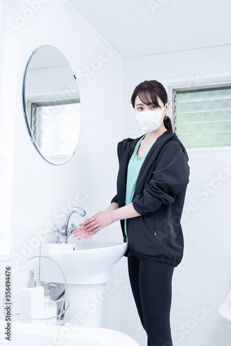 黒いジャージを着てマスクをして手を洗っている日本人女性
