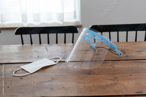 木のテーブルにマスクとフェイスシールドが置いてある