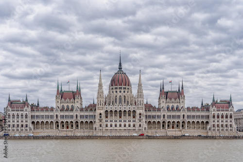 Hungarian Parliament facing Danube with clouds overhead in Budapest winter morning © Davidzfr
