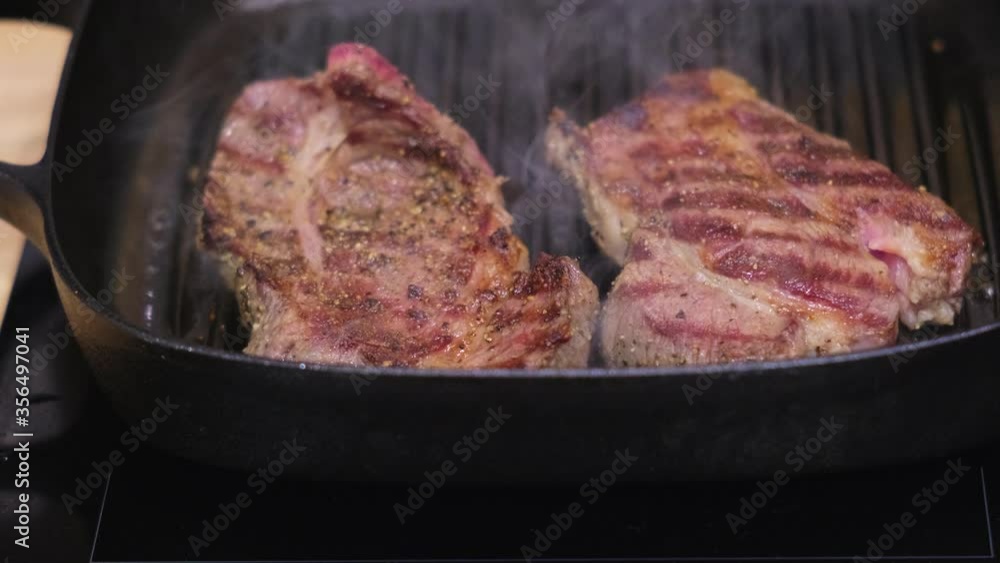 Meat steaks preparing with spices in grill pan Meat steaks preparing with spices in grill pan