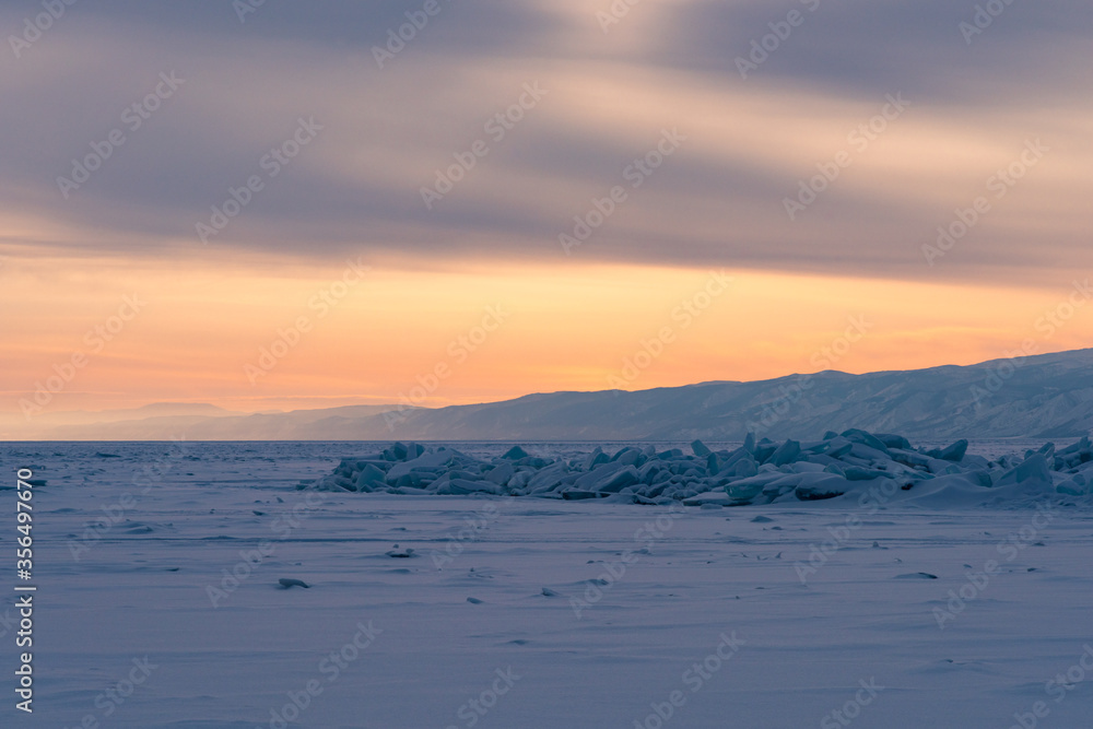 Early morning on the ice of lake Baikal against the background of mountains and ice