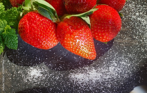 strawberries on black background with white sugar