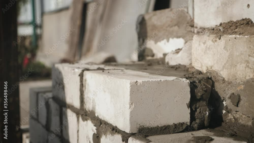 Construction worker or mason laying bricks and creating walls. Bricklayer laying bricks to make a wall. Building a cement block wall for a house. Construction worker or mason laying bricks and creating walls. Bricklayer laying bricks to make a wall. Building a cement block wall for a house.