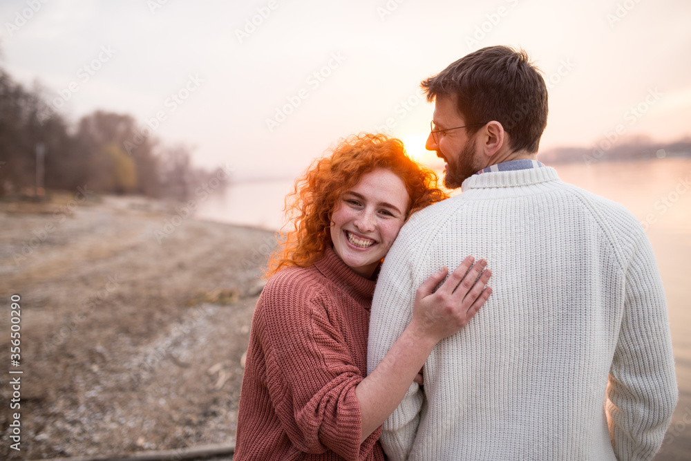 Fototapeta premium Couple cuddling while enjoying beautiful sunset together.