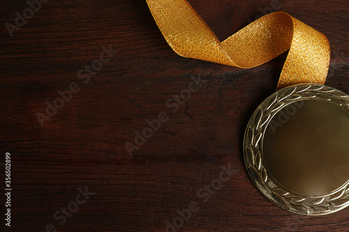 Gold medal with ribbon on wooden background, flat lay. Space for design photo