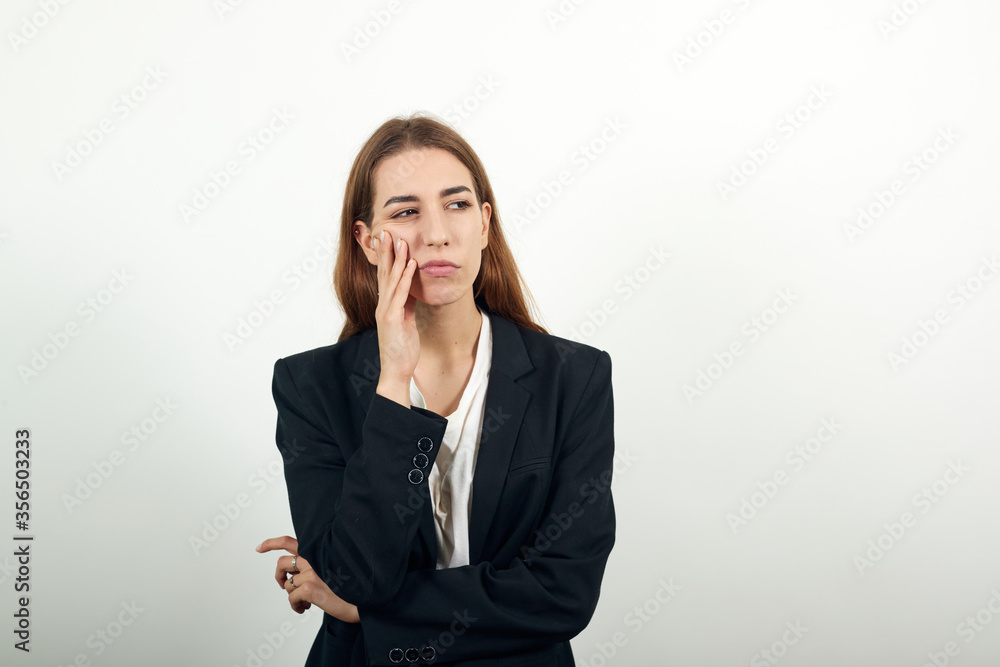 Hand on head thinking about question, pensive expression. Doubt. Thoughtful face. Using that incredibly sharp business mind. Young attractive woman with brown hair in a light t-shirt and black jacket