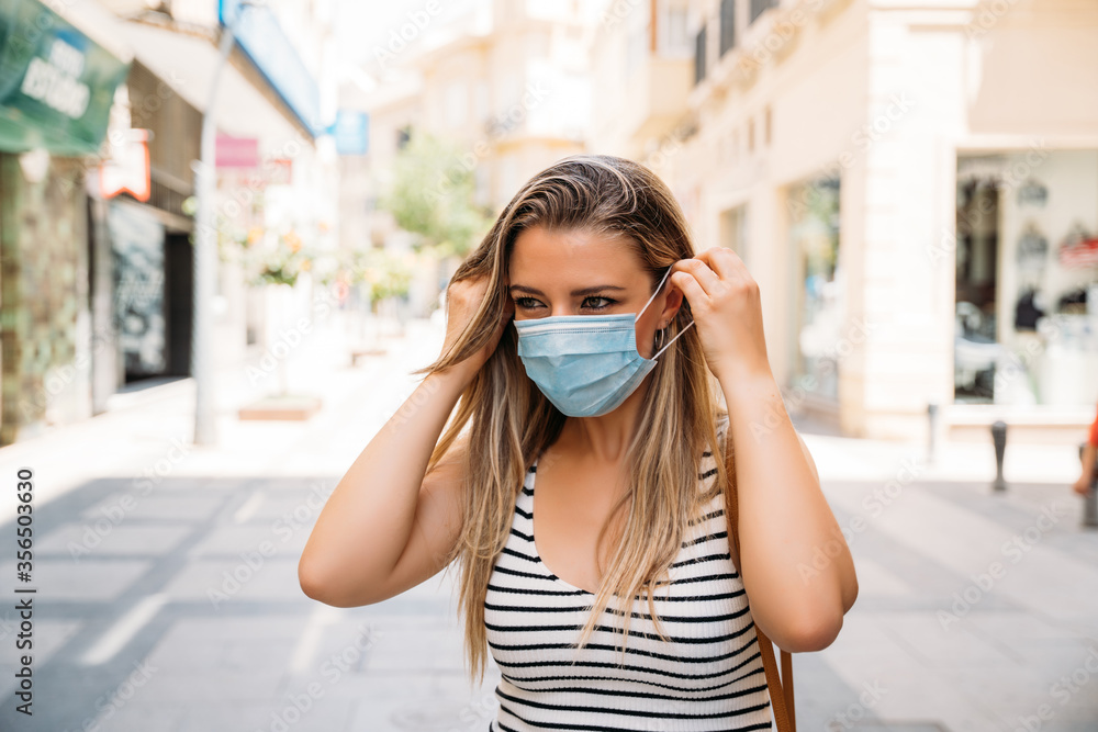 woman in mask in the city using her mobile phone during the coronavirus pandemic