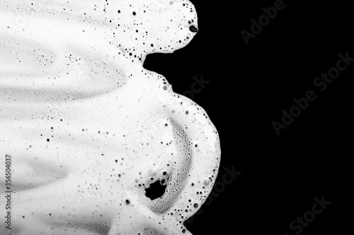 Beautiful white smear of shaving foam on a black background isolated. Men's hygiene, skin care. Gel is smudged. Closeup. Cosmetic products. Top view. Texture of cream. Copy space. Place for text.