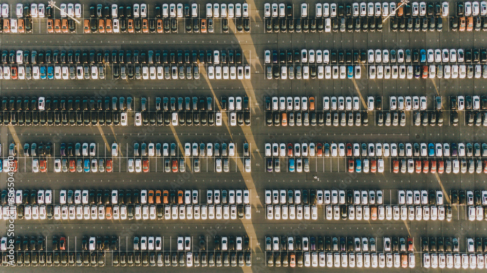 New cars stand in even rows in the territory of an automobile plant, aerial view. The economic crisis of overproduction, mass production, lack of demand.